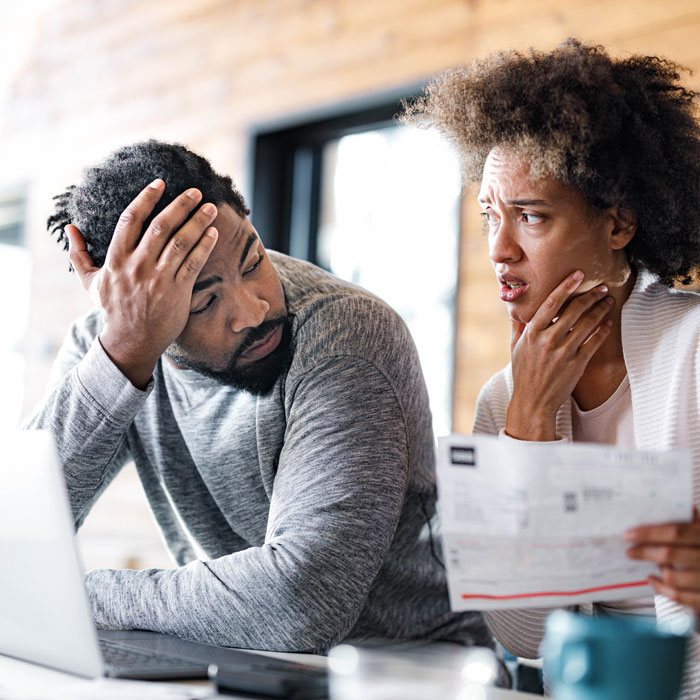 adult couple looking at each other with expressions of stress and confusion