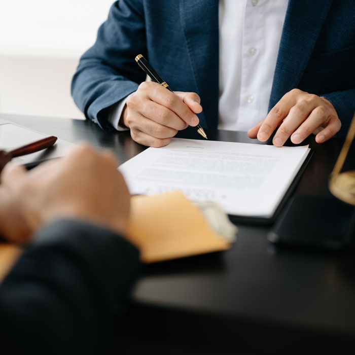 closeup of two men in suits signing document