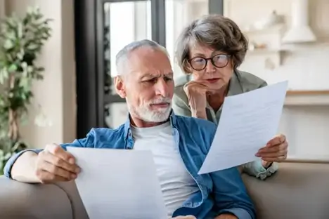 Senior couple reviewing estate planning documents together on a couch at home in Florida